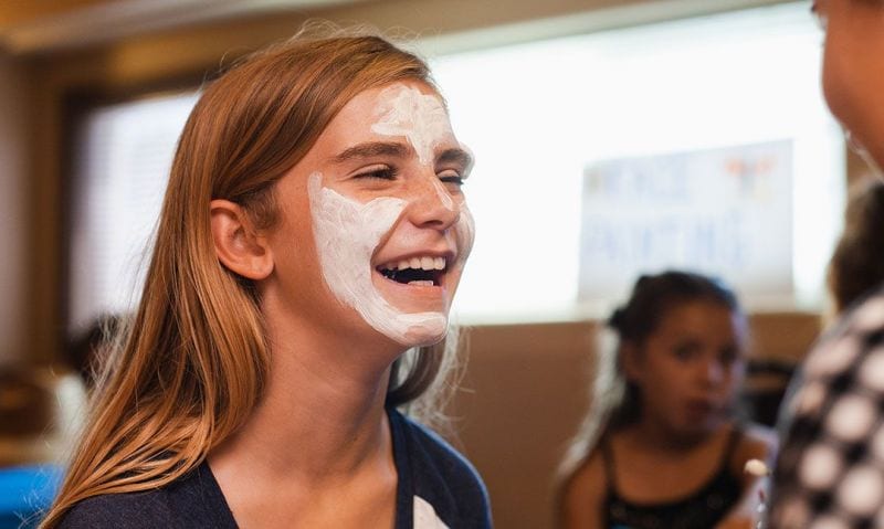 smiling girl gets face painted