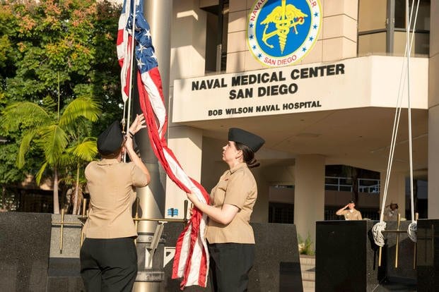 Hospitalman Claudia Clement (left) and Hospitalman Juliana Cha (right), both assigned to Naval Medical Center San Diego (NMCSD), raise the national ensign during morning colors at NMCSD