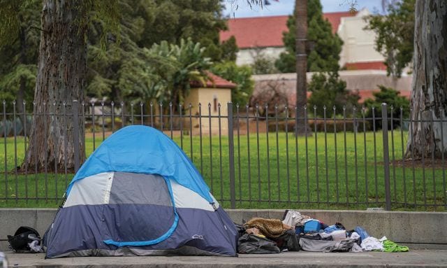 tent and other items of a homeless person on the sidewalk