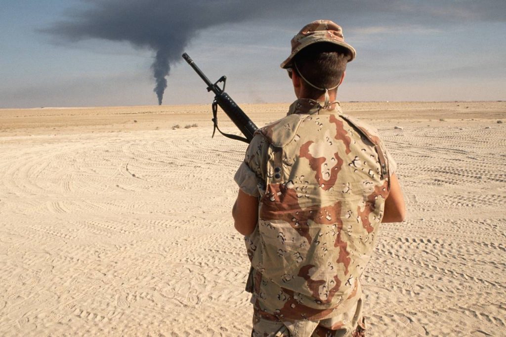 A U.S. soldier near Kuwait’s border with Iraq watches a plume of smoke on the horizon, Kuwait, January 1991. He was part of the U.S.-led coalition that drove Saddam Hussein’s forces out of Kuwait. (Photo: Peter Turnley/Corbis)