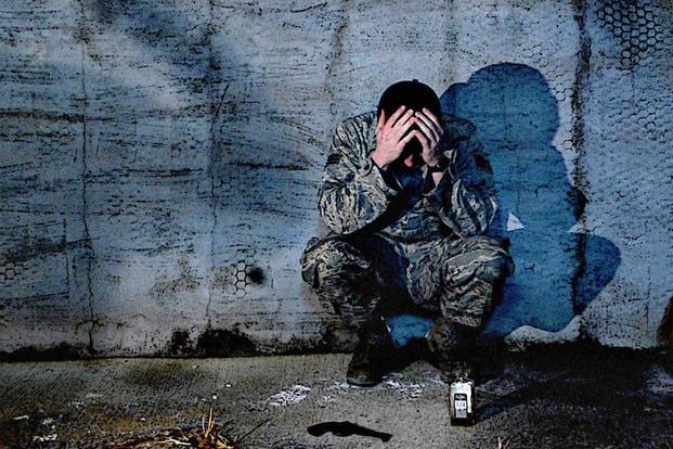military man crouched over with his head in his hands