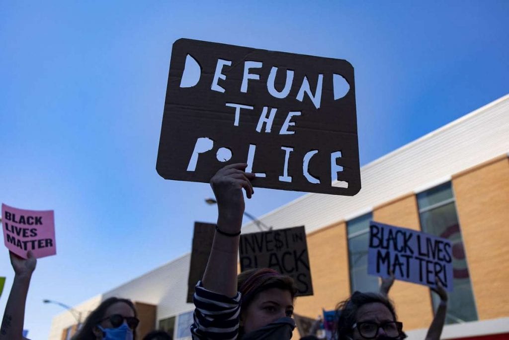 protestor holds a defund the police sign