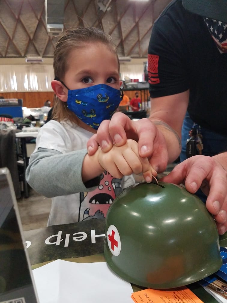 child putting change in a Helmet for Heroes bank