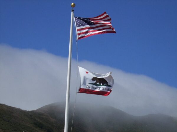 U.S. and California flags flying above California hills.