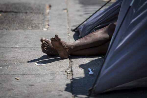 Homeless veteran's feet hang out of a tent in Skid Row, Los Angeles