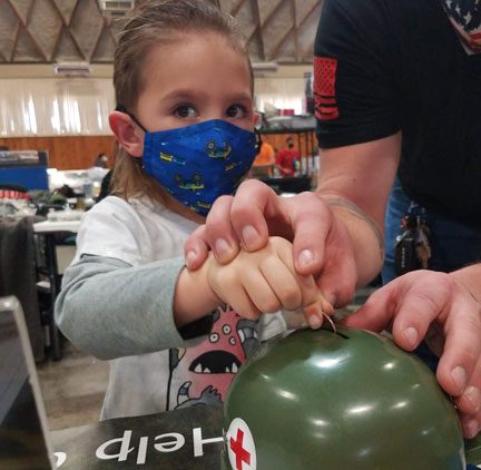 Masked girl putting coin in helmet