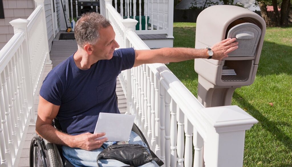 man in wheel chair getting mail in front of his adaptive house