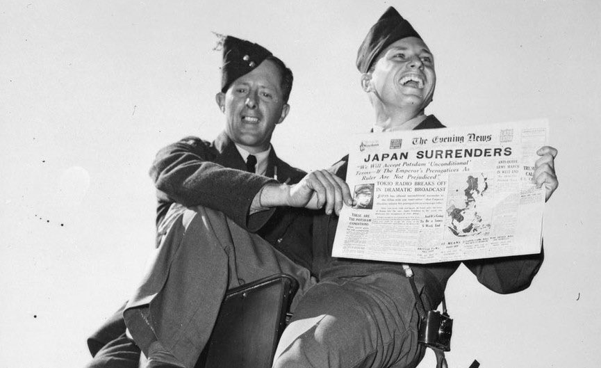 Two men holding a Japan Surrenders newspaper