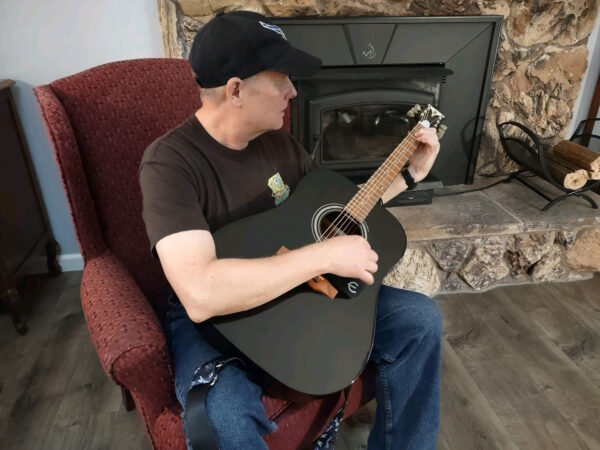 Retired Air Force Veteran, Mark Miller, playing the guitar he received through the Guitars for Vets program